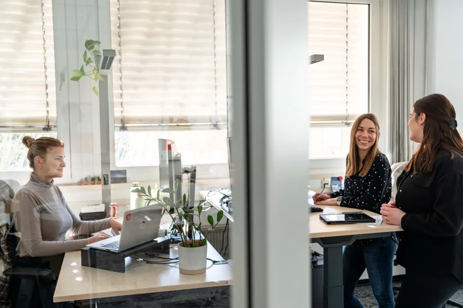 Drei Mitarbeiterinnen der effexx Unternehmensgruppe unterhalten sich am Schreibtisch.